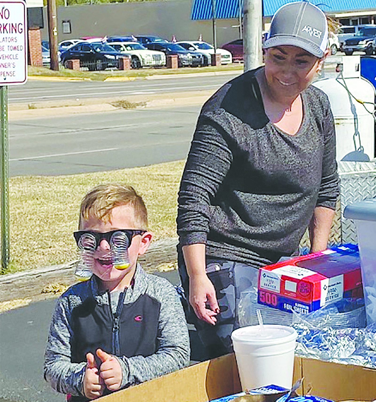 Asa Roman entertains his mom Lindsay Roman with his googly eyed glasses during the Teen Court Hamburger and Hotdog fundraiser held Saturday.