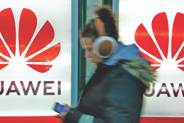 Photo provided A young woman with a smartphone and headphones walks past advertisement light boxes with the Huawei logo in Kiev, Ukraine.