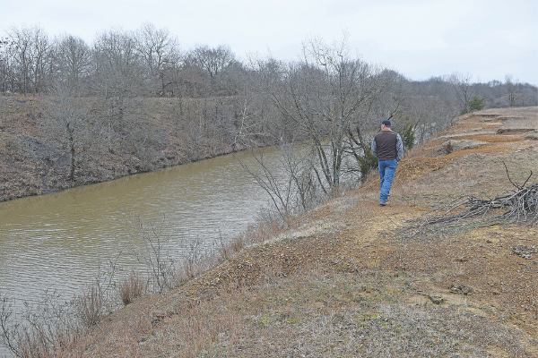 Trampas Tripp of Porum, an environmental technician and inspector with the Conservation Commission’s Abandoned Mine Land Reclamation Division, glances at a manmade channel in rural Haskell County. The embankment on both sides of the waterway is comprised of spoil piles from an abandoned coal mine. Photo by Bryan Painter