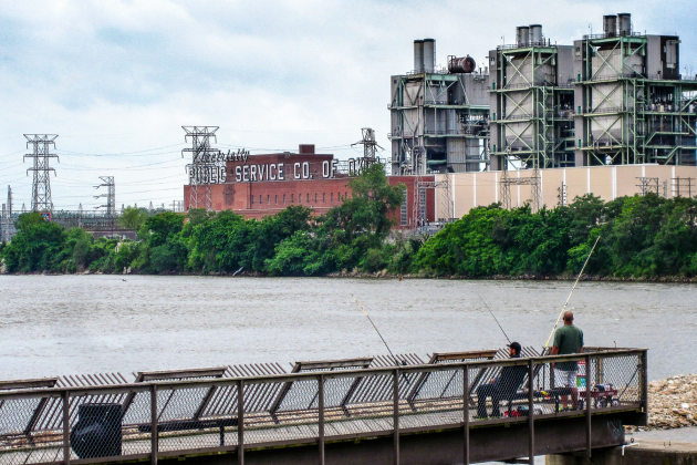 Two men fish in the Arkansas River on a pier facing the historic Public Service Co. of Oklahoma power plant in Tulsa.
