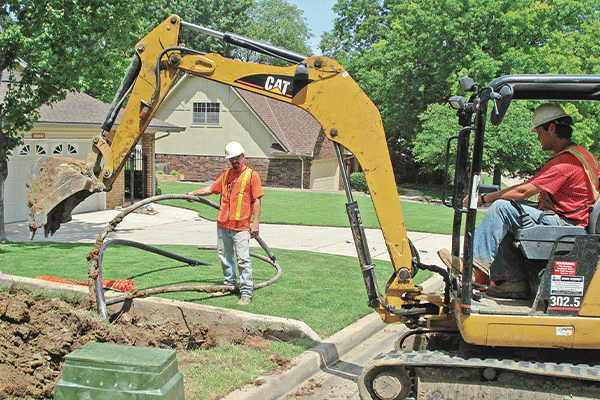 Photo provided by Public Service Co. of Oklahoma Public Service Co. of Oklahoma contractors excavate a trench in the front yard of a Tulsa area residence for burying power lines that previously were overhead distribution lines in the backyard.