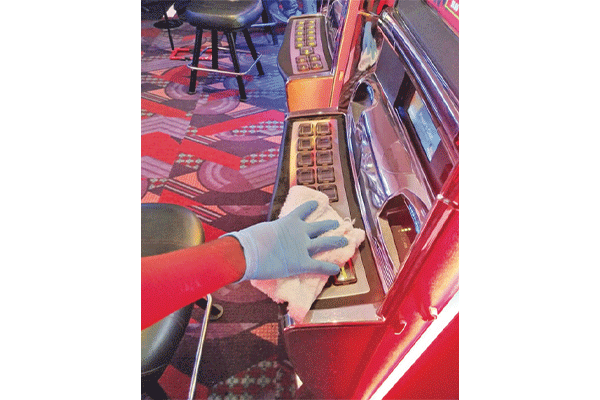 A worker wipes down a slot machine at Apache Casino Hotel in Lawton.