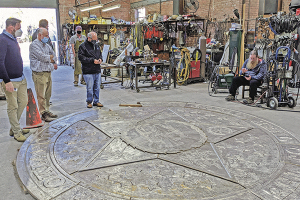 Photos by Trait Thompson: Members of the restoration team review progress on the new bronze state seal at The Foundry in Norman, in November 2020.