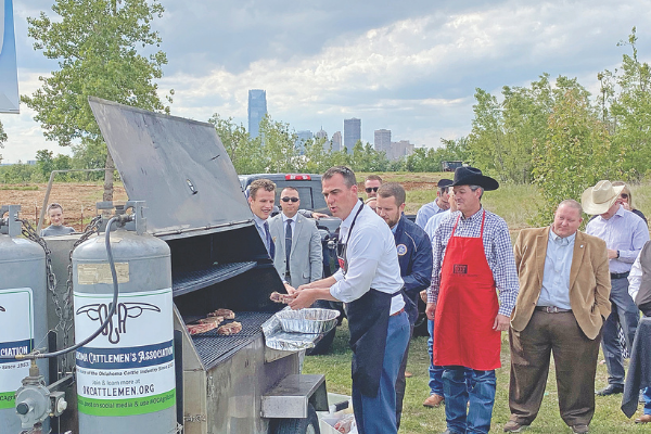 Oklahoma Gov. Kevin Stitt grills steak Wednesday in front of a PETA billboard the group purchased in response to the Governor’s vocal support of Oklahoma meat producers.