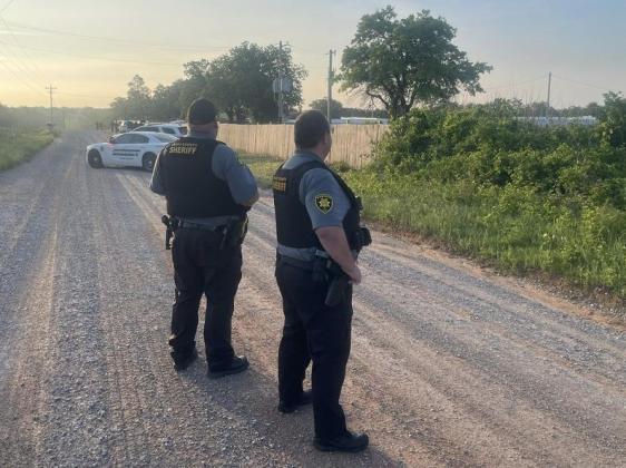 Two Grady County sheriff’s deputies stand in a rural road during one of the two raids on suspected illegal marijuana farms in the Rush Springs and Alex areas on May 16. GRADY COUNTY SHERIFF'S OFFICE FACEBOOK PAGE