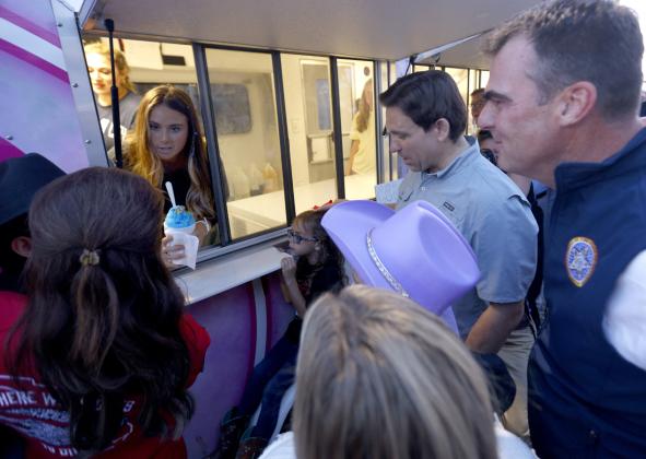 From the concession stand, Piper Stitt serves snow cones to 2024 presidential hopeful Florida Gov. Ron DeSantis; her father, Oklahoma Gov. Kevin Stitt and others during the Ponca City Rodeo. CHRISTOPHER BRYAN | SOUTHWEST LEDGER