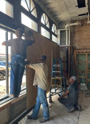 Rene Umana, kneeling, foreman in charge of construction in the renovation of the Savoy Hotel in downtown Chickasha, directs local workers hanging plywood panels pending installation of new windows in the front of the 121-year-old building. Umana has worked for California businessman and Savoy owner Chet Hitt for 19 years. Umana is being assisted in the renovation project by Hitt’s brother, Chuck; brothers Ethan and Jacob Compton, of Blanchard; and Jason Brown, of Alex. MIKE W. RAY | SOUTHWEST LEDGER