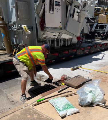 John Smith, left, and Zack Arnold, in drainage inlet, both with Environmental Cleanup Inc. from Wayne, Oklahoma, use “safety solvent” to sop up mineral oil that spilled from the transformer that slipped off a flatbed trailer and fell into a Chickasha street July 26. MIKE W. RAY | SOUTHWEST LEDGER