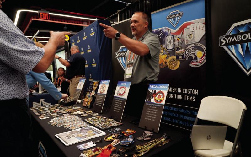 Ashley Payne | Southwest Ledger Chad Wessler with Symbol Arts, a custom badge and recognition product supplier, speaks with guests Wednesday during the FIRES Symposium at the FISTA Innovation Park.