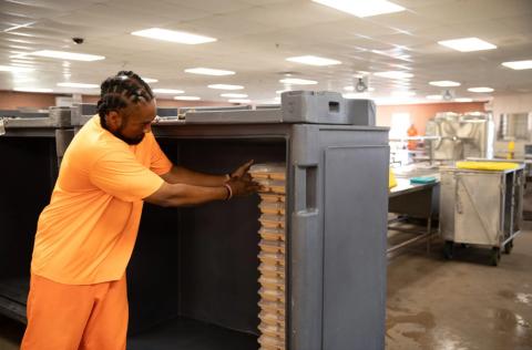 A prisoner stacks food trays in the kitchen of the Joseph Harp Correctional Center on Oct. 10, 2024. Brent Fuchs | Oklahoma Watch
