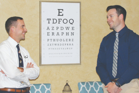 Southwest Ledger photo by Curtis Awbrey, Optometrists Bryce Geiger and Michael Rice stand by the eye chart at Geiger Eye Care’s Elgin office. Both doctors are second-generation optometrists who attended Cameron University and Northeastern State University College of Optometry in Tahlequah.