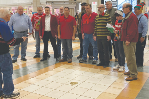 Southwest Ledger photo by Curtis Awbrey                            Led by Bill Penn, far left, Southwest Pride Barbershop Chorus members are, from left, Don Ward, David Lindley, Neil West, Ben Good, David Hastings, Coleman Gray, Earl Emerson, Joe Crane, Troy Hamilton, Chandler Moncreiff, Tom Love and Joel Blomgren. Southwest Pride Chorus brought Christmas cheer to an audience of holiday shoppers as the group sang Christmas carols during the Ware District Holiday Market held at Central Mall Thursday evening.