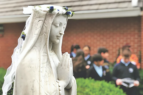 Photo provided: Students pass behind a statue on the campus of St. Mary's Catholic School in Lawton. 