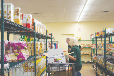 Ledger file photo by Curtis Awbrey - Volunteers Susan McCann and Larry Travis restock shelves at the Lawton Food bank. 