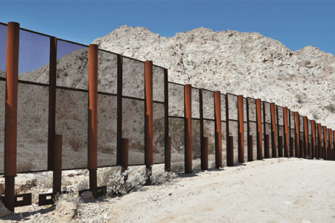 A large steel fence borders Mexico and the United States at the Tinajas Altas Mountains in Arizona.
