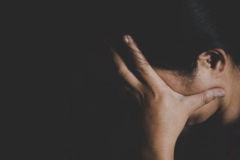 A woman holding her face in darkness.
