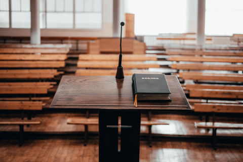 Podium with the Holy Bible in front of empty church seating