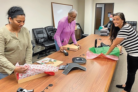 Office of Juvenile Affairs Chief of Staff Constanzia Nizza, right, and OJA employees Vijayalakshmi Swamidurai, left, and Shelly Richardson help wrap gifts provided by the Santa Claus Commission for more than 200 youths spending Christmas in the 11 group homes across the state that have contracts with OJA and the agency’s two secure-care treatment facilities. PHOTO PROVIDED