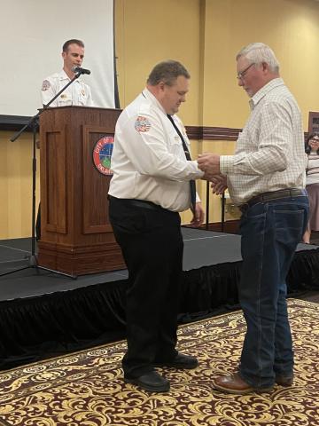 From the left, Assistant Fire Chief Brent Baggett looks on as Lawton Fire Chief Jared Williams has his collar brass pinned on by Williams’ father, Tommie Williams. Lawton officials hosted a pinning ceremony for Jared Williams, Lawton’s newest fire chief, on Monday.  Eric Swanson