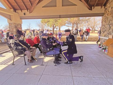 As scores of funeral attendees gather to pay their respects, members of veteran support groups receive flags honoring U.S. Army Specialist 4 Ronnie Richards, U.S. Army Private Ralph Sandy, U.S. Air Force Master Sergeant Louis Volak, and U.S. Marine Private Donald Wilson, the four unclaimed veterans interred at Fort Sill National Cemetery.  Photo by Curtis Awbrey