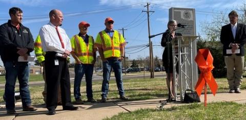 Oklahoma Department of Transportation Deputy Director Dawn Sullivan reads the names of ODOT’s 61 fallen workers during a Moment of Silence ceremony for workers at the end of National Work Zone Awareness Week. She was joined by Secretary of Transportation Tim Gatz, right; ODOT Director of Operations Shawn Davis, left; and Oklahoma Turnpike Authority Deputy Director Joe Echelle, far left; along with OTA maintenance workers Kenny Baker and Jeremy Smart. Echelle read the names of OTA’s 11 fallen workers.  Photo