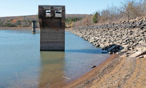 Fourche Maline Dam #7M, which created Lloyd Church Lake in Latimer County, will be raised 6 feet for enhanced safety and to meet Wilburton’s future water needs. Stone riprap along the embankment, as well as the lake’s flood control and municipal water supply towers, exhibit evidence that water levels in the reservoir have been low recently.  LEDGER PHOTO by MICHAEL D. DUNCAN