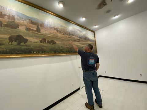 Paul Frable, board president for Holy City of the Wichitas, points out different structures on the recently restored mural. The mural was found in a damp museum storage room in 2017. Photo by Curtis Awbrey