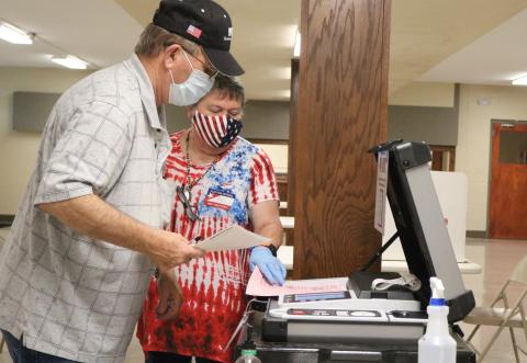 Ottawa County precinct worker Kay Boman Harvey helps Ronnie Barnes feed his ballots into the voting machine at the Miami Civic Center in this 2020 file photo. Ottawa County, located in Oklahoma’s northeast corner, gets its TV news from the Joplin, Mo. market. It ranked 74th among the state’s 77 counties for voter turnout, with less than half of its registered voters casting a ballot in the 2022 gubernatorial election. KAYLEA HUTSON-MILLER | FOR OKLAHOMA WATCH