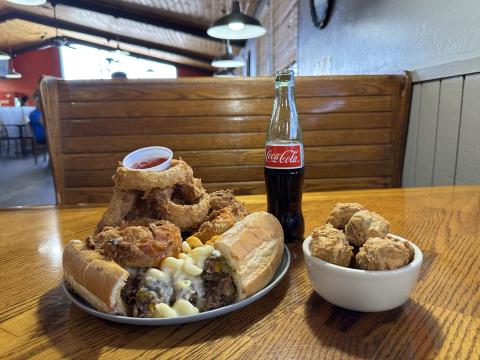 PhillyHoma’s ‘Dare You’ cheesesteak features a double serving of Philadelphia-style chopped steak with onions, mushrooms, green and red bell peppers, jalapeños, bacon, pepperoni, smothered in rich macaroni and cheese and a zing of buffalo sauce and onion rings all on a toasted bun with a side of onion rings. Add some delectable fried mushrooms and a glass bottle of Coca-Cola, this meal is a delicious culinary masterpiece. CURTIS AWBREY | SOUTHWEST LEDGER