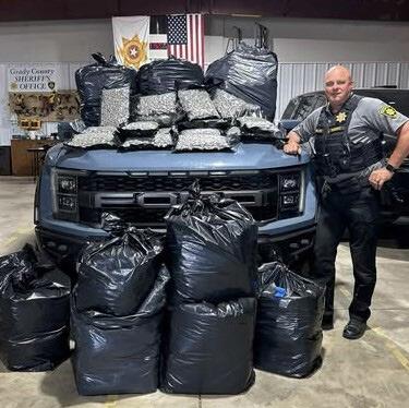 Grady County Sheriff’s Office Grady County Deputy Matt Wallace is shown with some of the 900-plus pounds of marijuana confiscated last week after a traffic stop he made north of Chickasha and a subsequent raid on a rural marijuana farm.