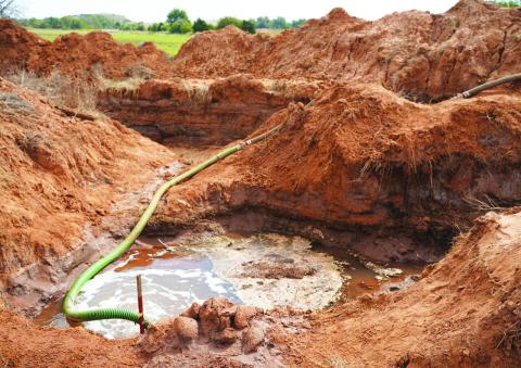 Saltwater flowing into this pit in Caddo County is pumped into this hose, which is connected to several semi-trailer tanker trucks each day and hauled away to a saltwater disposal well north of Hydro in Blaine County. Five Mile Creek was contaminated when highly concentrated saltwater began discharging from this site in mid-September. Kyletta Ray | Southwest Ledger